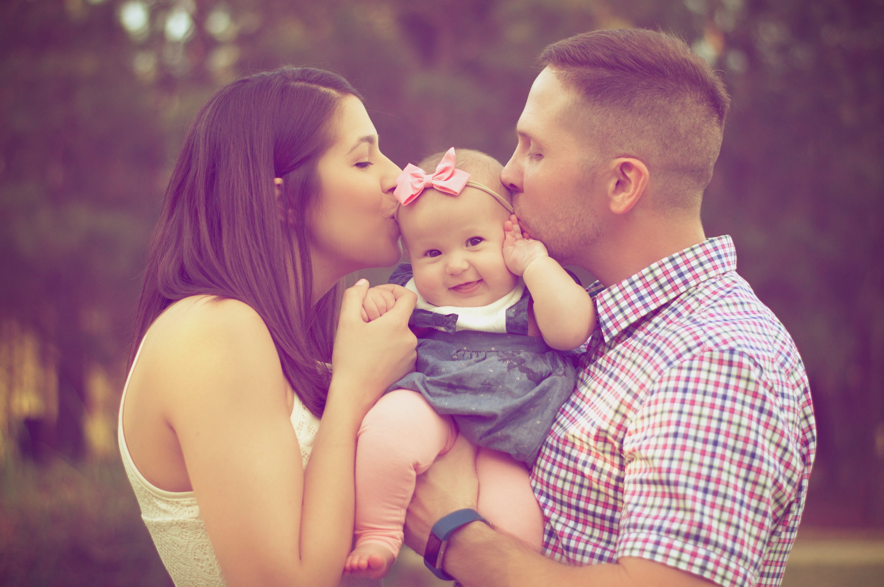mom and dad kissing their baby girl
