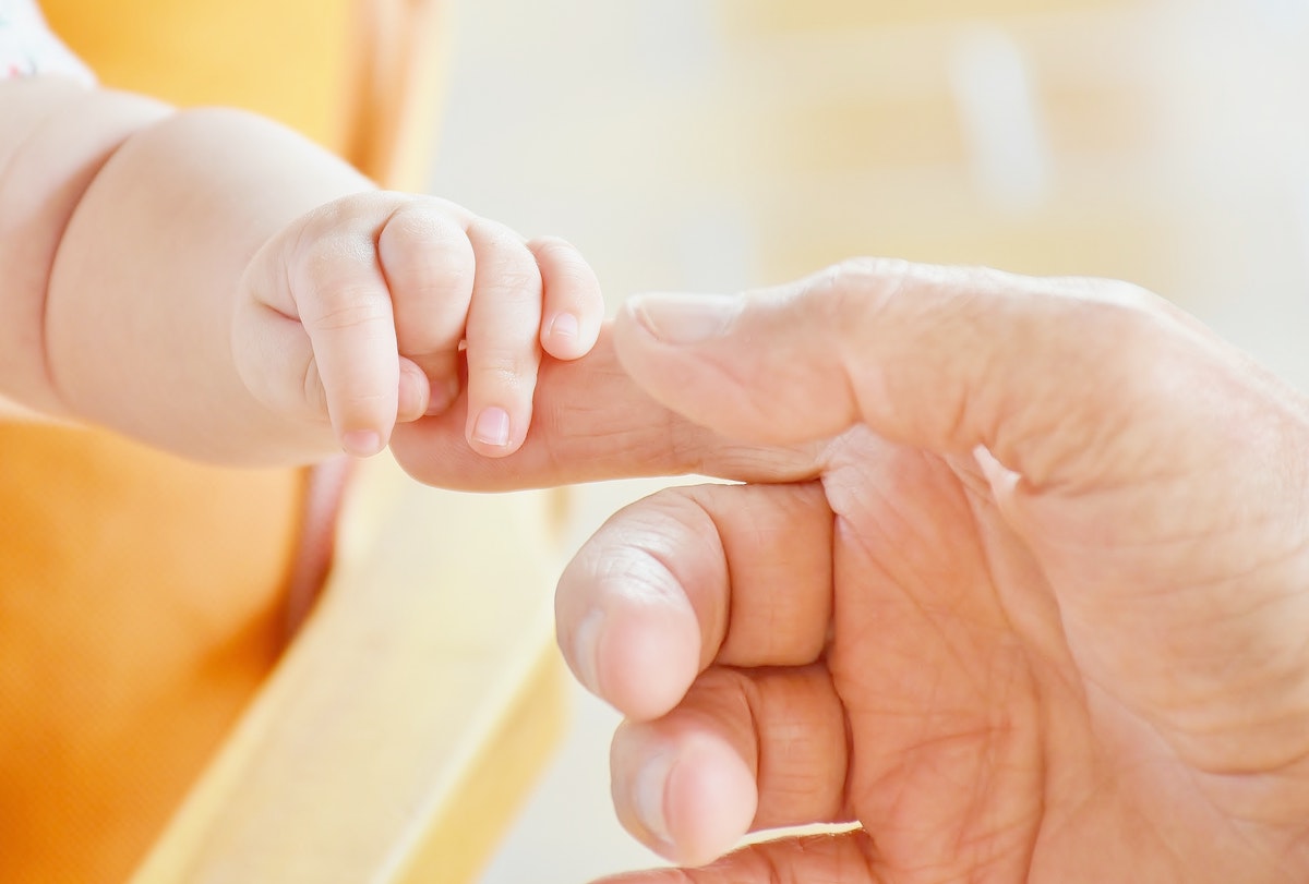IVF baby holding its father's finger