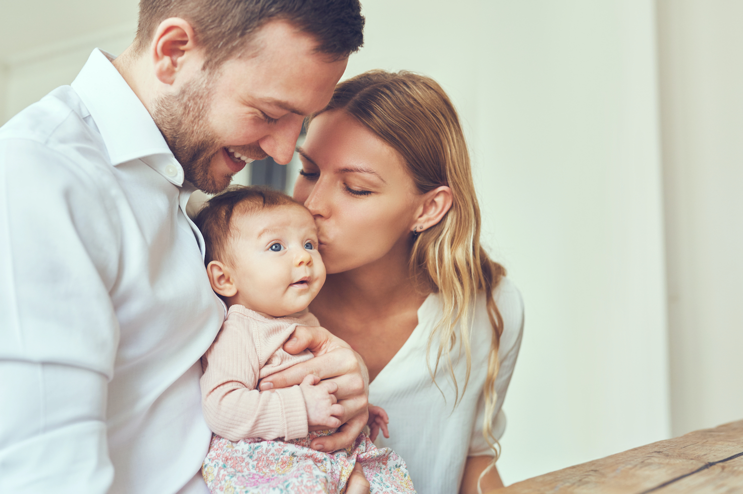 parents holding and kissing their baby