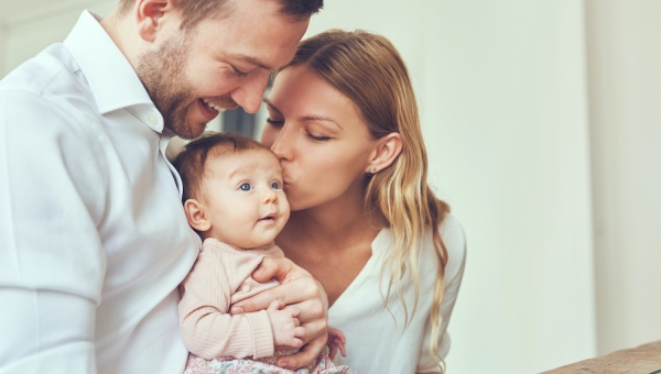 parents holding and kissing their baby
