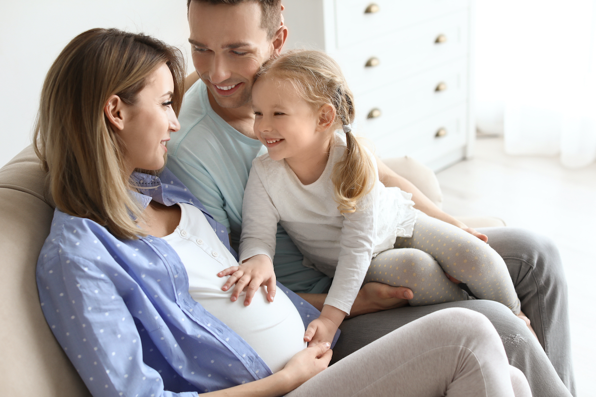 Dad with pregnant mom after IVF treatment and daughter feeling baby kick
