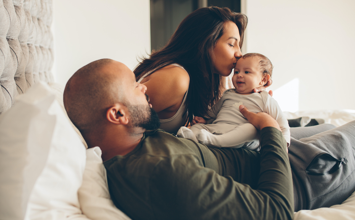 Multiracial couple playing with their IVF baby