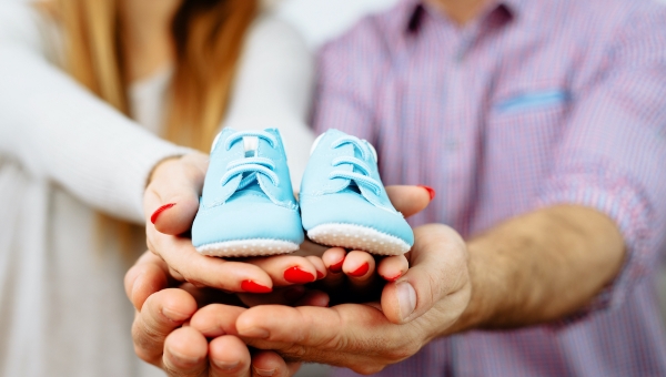 Expecting couple holding light blue baby shoes
